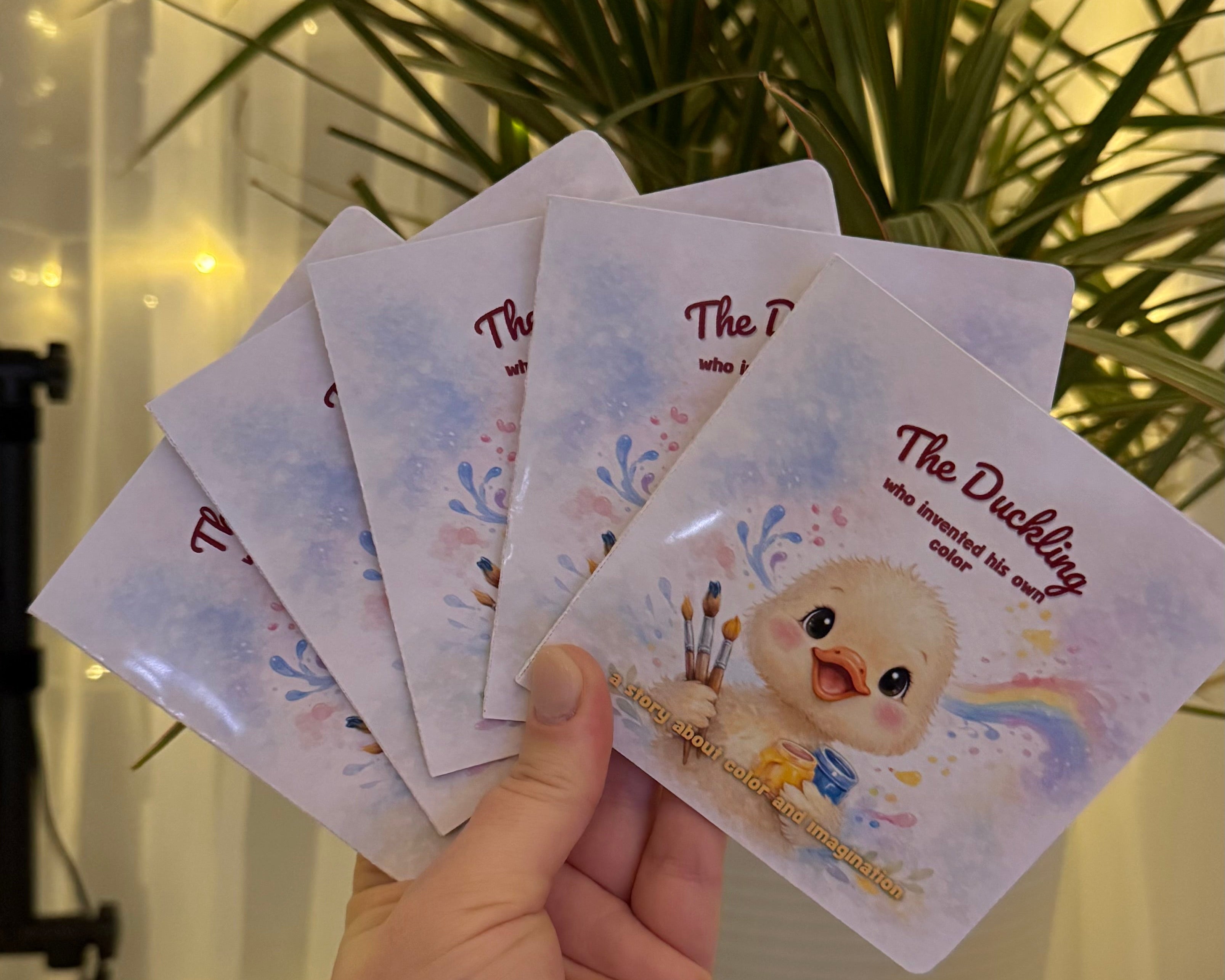 Hand holding a set of small cards with a cartoon character on a blurred indoor background